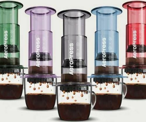 Cinq cafetières AeroPress colorées avec tasses remplies de café.
