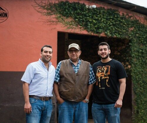 Trois hommes posent devant un bâtiment.