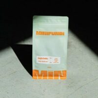 Paquet de café Minifundi sur fond ensoleillé.