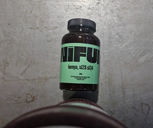 Bouteille de café NIFU Kenya sur table grise.